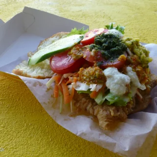 Bake and shark piled with salad and sauces in a takeaway box