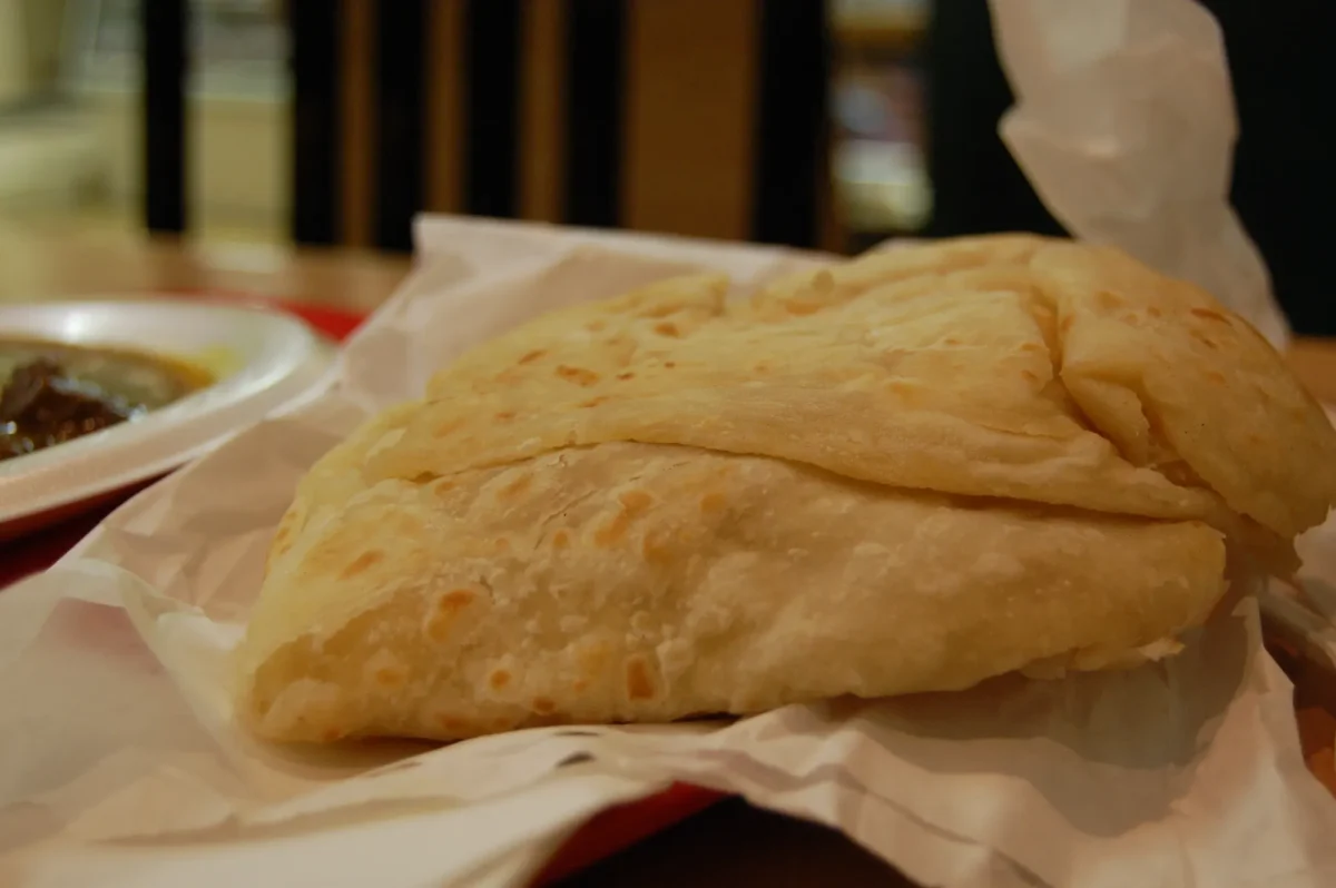 A paratha roti on paper, torn into soft layers