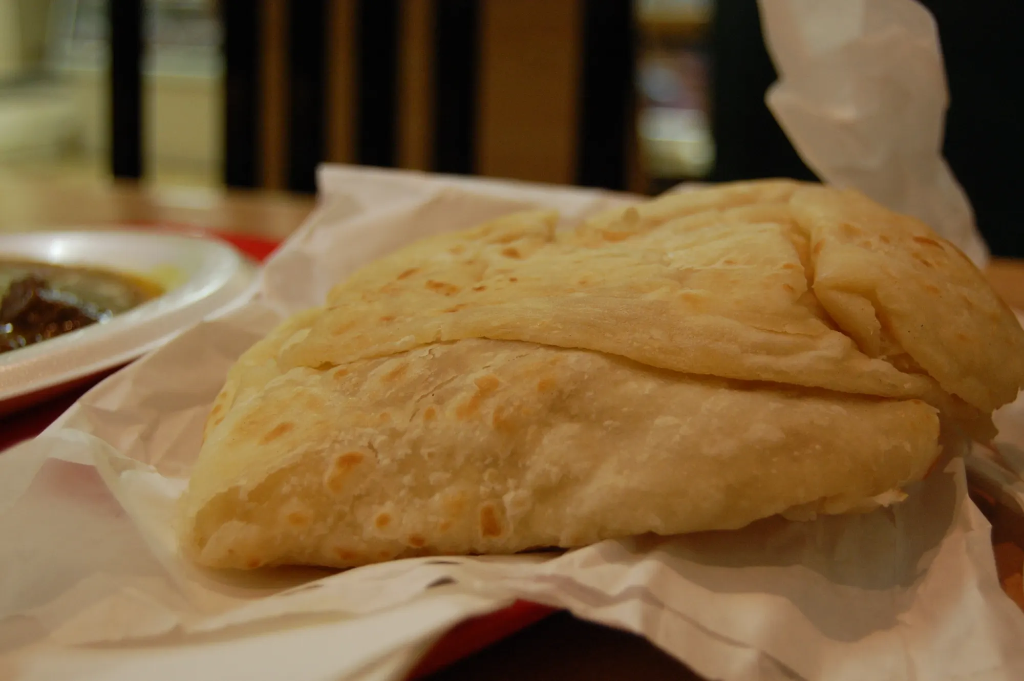A paratha roti on paper, torn into soft layers