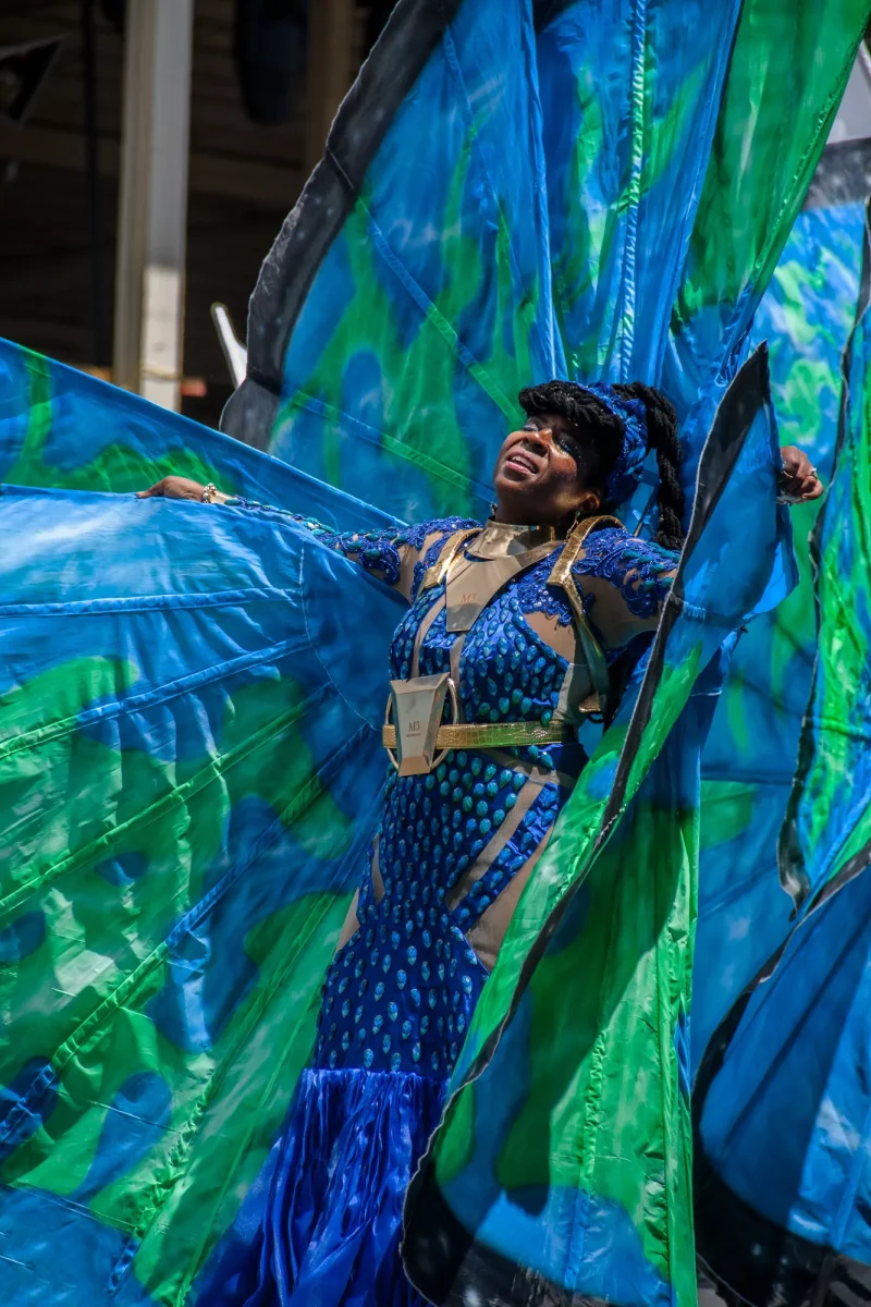 A masquerader in a blue and green winged costume at Trinidad and Tobago Carnival