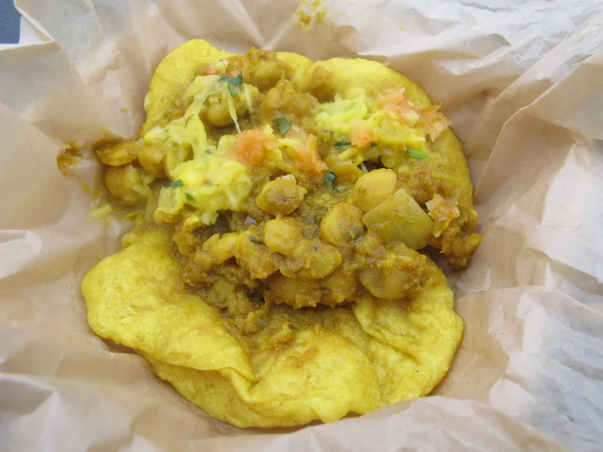Doubles heaped with channa and cucumber chutney on paper