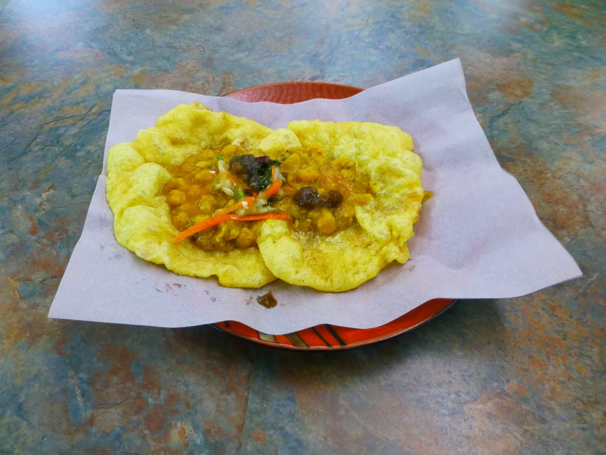Doubles: two soft yellow bara topped with curried channa, served on paper