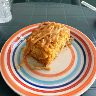 A slice of baked macaroni pie on a striped plate