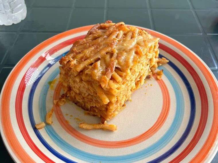 A slice of baked macaroni pie on a striped plate
