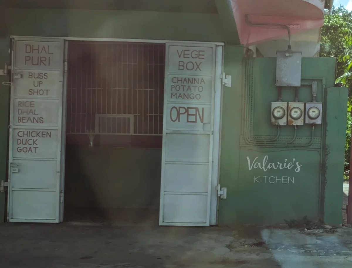 A roadside food place in Freeport, Trinidad, with hand-painted signs for buss up shut and dhal puri
