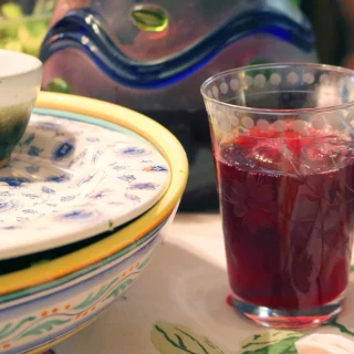 A glass of deep red hibiscus (sorrel) drink on a set table